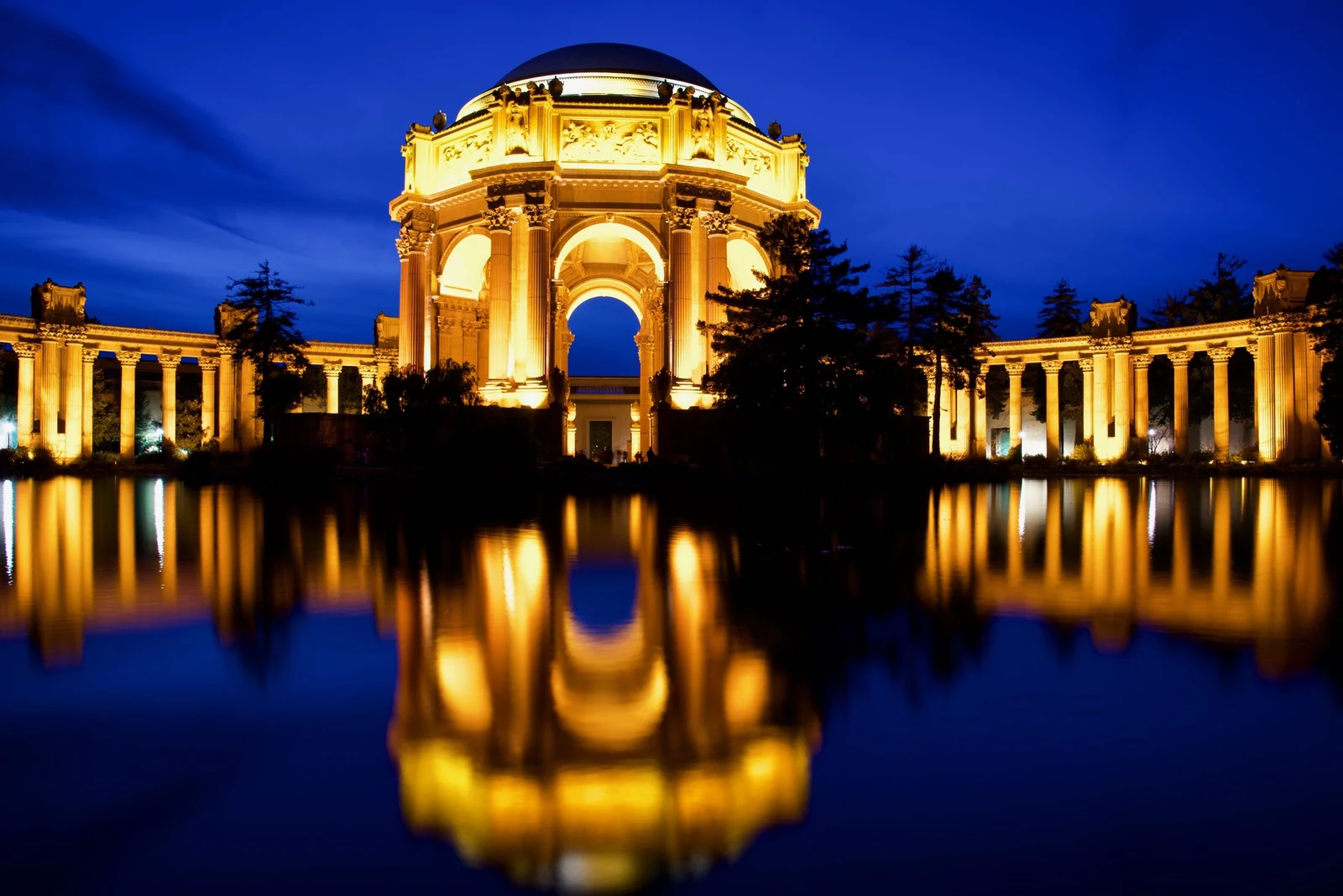 Golden light on the Palace of Fine Arts rotunda reflected in the lagoon at blue hour