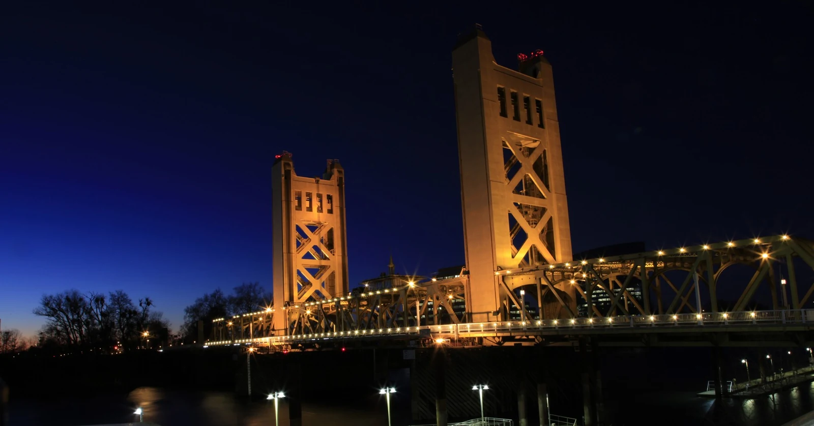 Sacramento Tower Bridge illuminated in gold against a deep blue twilight sky